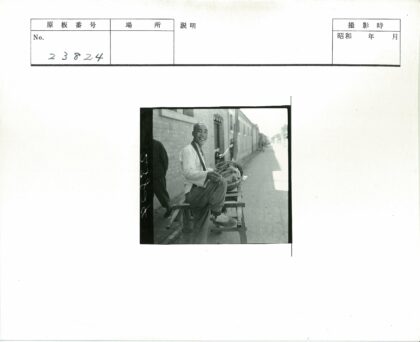 微笑男子坐手推车砖房背景.jpg
