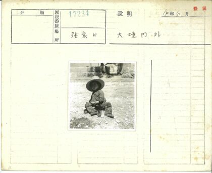 戴帽子孩子坐户外建筑树背景.jpg