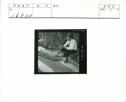 戴帽男子坐布袋旁辣椒布背景植物篮.jpg