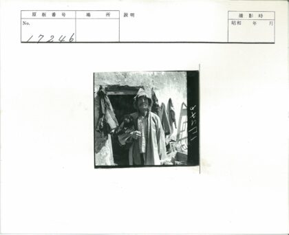 戴帽男子抱小狗与挂衣墙前.jpg