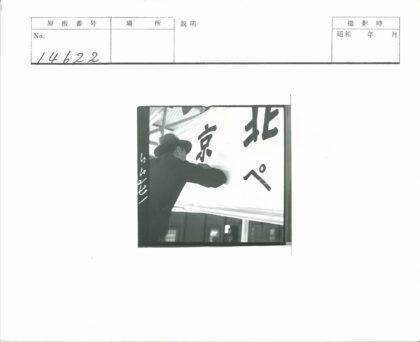 戴帽男子日文金属屋顶下举牌.jpg