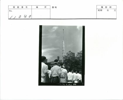 户外仰望旗杆的人群与砖砌建筑.jpg