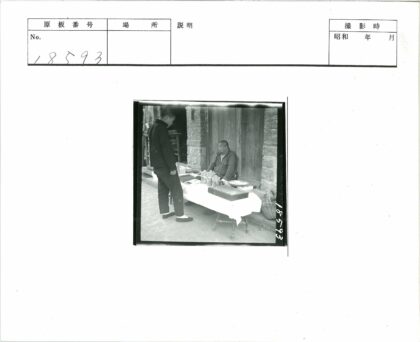 户外桌旁男子与砖木建筑.jpg