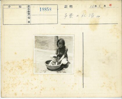 户外砖墙前母亲给孩子洗澡.jpg