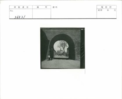 持木棒男子穿过砖砌拱门街景.jpg