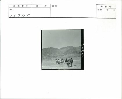 晴朗天空下穿越贫瘠田野向山脉行进的人群.jpg