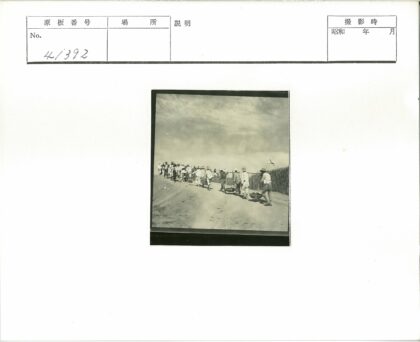 村民举旗行走泥泞田间小路.jpg