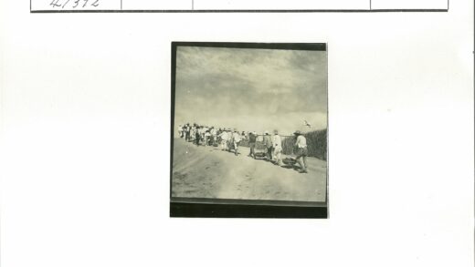 村民举旗行走泥泞田间小路.jpg