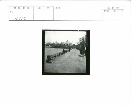 水边土路行人建筑枯树景.jpg