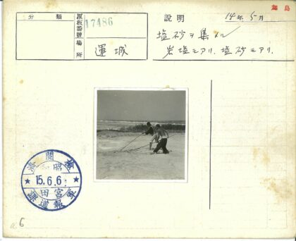 海岸边两人持长棍行走.jpg