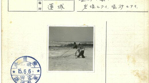 海岸边两人持长棍行走.jpg