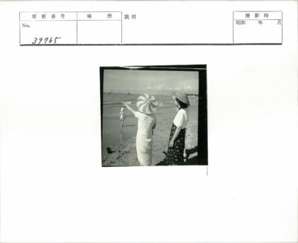 海边戴帽女人与孩童沙滩时光.jpg