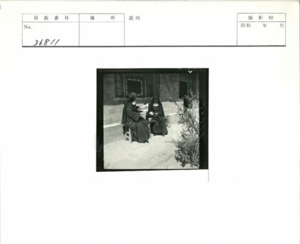 深色长袍人物在砖房外交谈.jpg