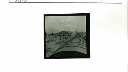 火车停靠建筑旁轨道行人散步背景有船.jpg