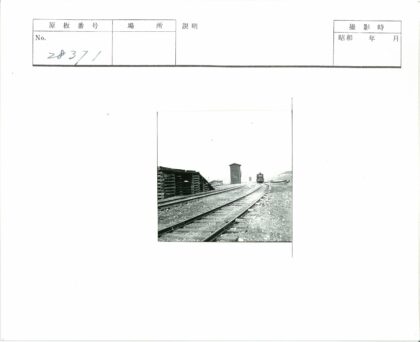 火车行驶于开阔地旁有木托盘建筑.jpg
