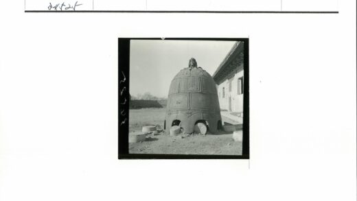 男子坐铭文钟前传统建筑.jpg