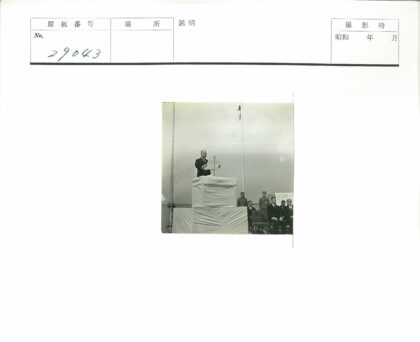 男子平台演讲群众围观高杆旗帜.jpg