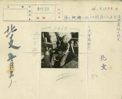 男子持绳站木轮旁.jpg