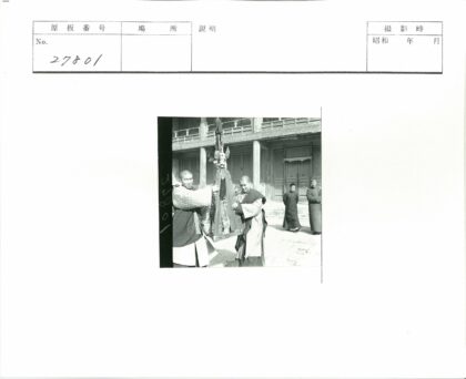 男子持骷髅三角物木屋前合影.jpg