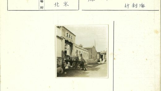男子推木车穿过汉字大门街景.jpg