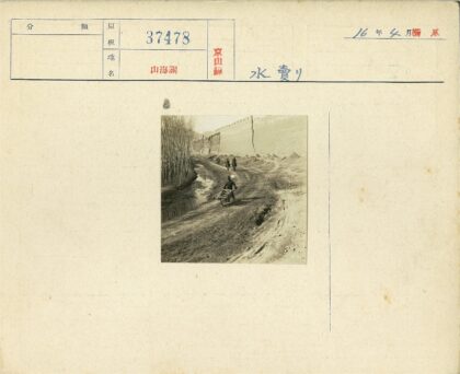 男子推独轮车沿水渠骑行背景.jpg