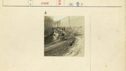 男子推独轮车沿水渠骑行背景.jpg