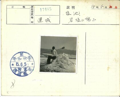 白衫男子坐盐堆持长棍山景.jpg