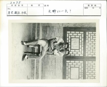 砖墙窗前两男子坐椅.jpg