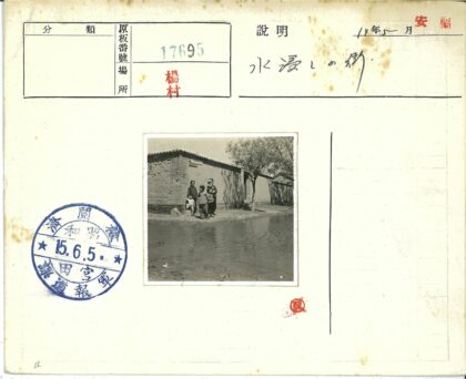 砖房前水坑旁的人群与树.jpg