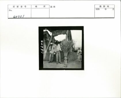 砖房旁持乐器男子合影.jpg