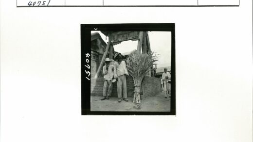 砖房旁持乐器男子合影.jpg