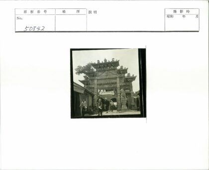 精美牌坊下行人走过石狮雕像.jpg