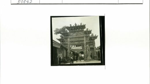 精美牌坊下行人走过石狮雕像.jpg