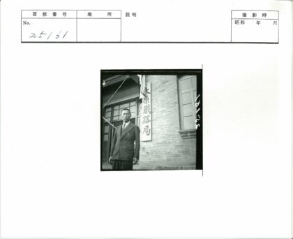西装男子站在砖房汉字牌前.jpg