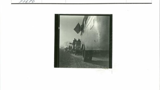 车队行驶土路人举旗晴空秃树.jpg