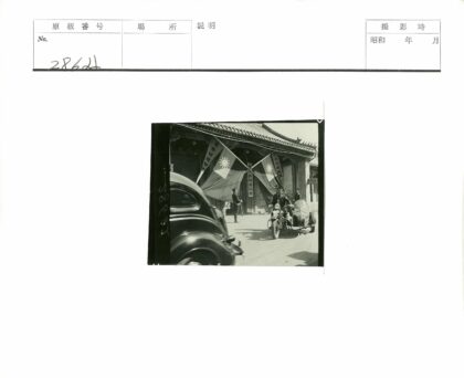 黑色轿车与挎斗摩托车经过旗帜建筑.jpg