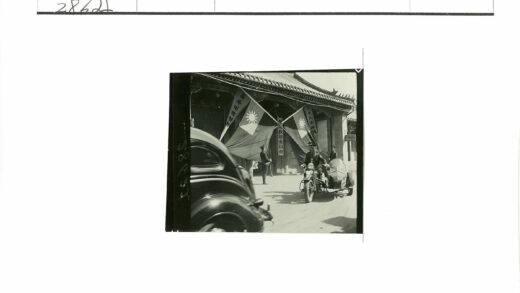 黑色轿车与挎斗摩托车经过旗帜建筑.jpg