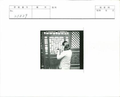 齐肩长发者持物立于几何木格门前.jpg