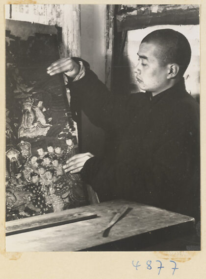 【jpg清晰版】男子在卷轴装裱店中将重新装裱的卷轴画从干燥板上取下.jpg