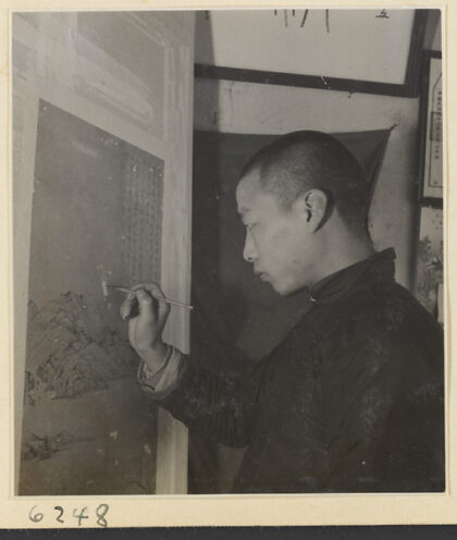 【jpg清晰版】装裱店内景男子修补悬挂在装板上的画作缺损处.jpg