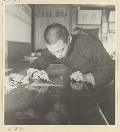 【jpg清晰版】装裱店内景男子用铁镊子清除画作背面的纸屑.jpg